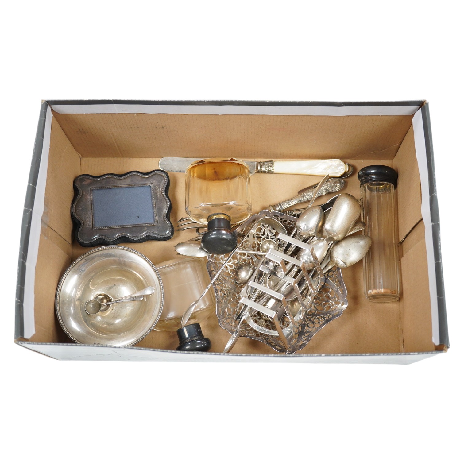 A group of assorted small silverwares including flatware, a toast rack and a pierced bon bon dish, 15.5 oz of weighable silver. Condition - fair